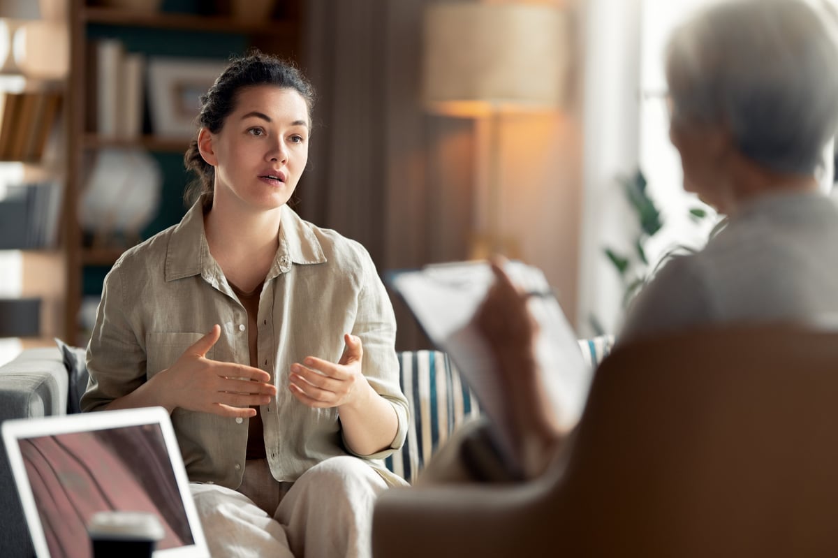 A young woman engaged in an empathetic conversation with a mental health professional in a comfortable office